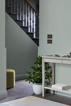 a white table sitting in front of a stair case next to a potted plant