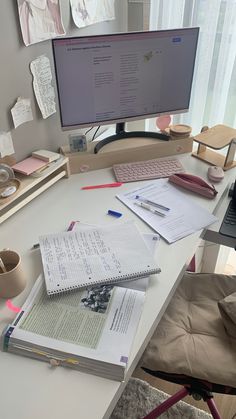 a desk with a computer monitor, keyboard and papers on it