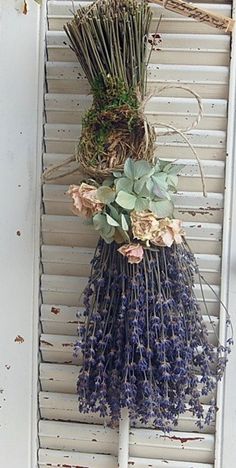 a bunch of dried flowers hanging on the side of a building with shutters behind them