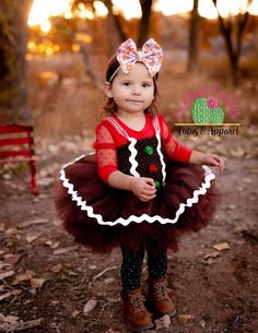 This adorable gingerbread tutu dress features brown glitter tulle and frosting! The straps are adjustable by tightening the bow in the back. Skirt length: 0-6 months is approximately 4 inches long. 6 mos - 2T is approximately 6 inches long. 3-4T is approximately 8 inches long. 5-6T is approximately 10 inches long.Skirt length: 3-9 months is approximately 4 inches long. 9-24 months is approximately 5 inches long. 3/4T is approximately 6 inches long. 5/6T is approximately 8 inches long. Cute Fitted Christmas Tutu Dress, Cute Fitted Tutu Dress For Christmas, Fitted Tulle Tutu Dress For Holiday, Cute Christmas Tutu Dress For Festive Occasions, Cute Christmas Tutu Dress With Ruffles, Cute Fitted Tutu Dress For Festive Occasions, Cute Fitted Tutu Dress For Festivities, Cute Christmas Tutu Dress, Gingerbread Girl Costume