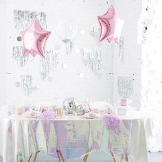 a table with pink umbrellas hanging from it's ceiling in front of a white wall