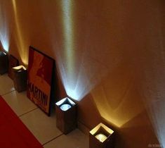 some lights that are on the side of a wall near a red carpet and white walls