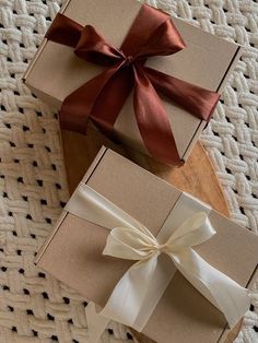 two brown boxes with white ribbons and bows