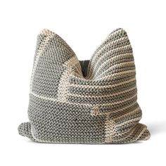 a gray and white knitted pillow on a white background