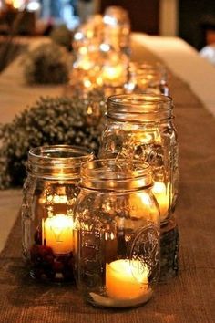 several mason jars filled with lit candles on a table