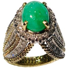 Very unique, high fashion estate ring features a bright, light apple green, variegated, oval cut jade stone, prong set and surrounded by a sparkling halo of 20 round brilliant diamonds. Elaborate side detail features 5 ropes of 14 karat yellow gold, alternating with 4 insets of 5 pave set round brilliant diamonds on both sides, which come together in an inverted "V" shape at the top and bottom of the head of the ring, and taper to the shank of the ring. Oval Jade cabochon measures 10.23 mm x 8.4 mm x 6 mm and weighs approximately 3.9 carats. 20 diamonds measure 2 mm in diameter and weigh approximately .60 carats. 40 diamonds measure 1.3 mm in diameter and weigh approximately .40 carats. Approximately 1 carat total diamond weight. Diamonds are VS in clarity and G in color. Hallmarked, "14k Luxury Lime Green Oval Rings, Luxury Emerald Ring With Oval Cabochon, Luxury Oval Cabochon Emerald Ring, Formal Green Cabochon Emerald Ring, Luxury Emerald Ring With Oval Cabochon And 17 Jewels, Luxury Oval Cabochon Emerald Ring With 17 Jewels, Luxury Green Pear-shaped Jewelry, Exquisite Oval Green Emerald Ring, Exquisite Green Oval Emerald Ring