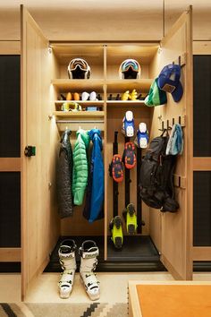 a wooden closet filled with lots of coats and snow shoes next to a rug on the floor