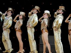 a group of people standing next to each other in front of a stage with hats on