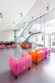 an empty room with pink and orange couches in the foreground, stairs in the background