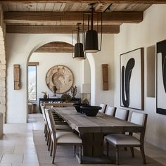 a dining room table and chairs in front of a stone wall with art on it