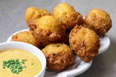 some fried food on a white plate with a bowl of dipping sauce