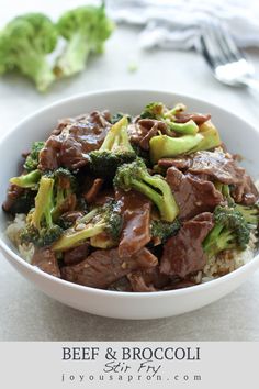 a bowl filled with beef and broccoli on top of rice next to a fork