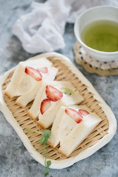 three slices of cake with strawberries on top and a cup of green tea