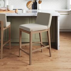 two stools in the middle of a kitchen with white counter tops and wooden floors