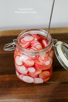 a jar filled with sliced up radishes sitting on top of a wooden table