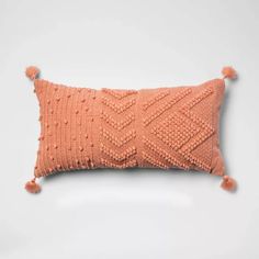 an orange knitted pillow with pom - poms on the front and back