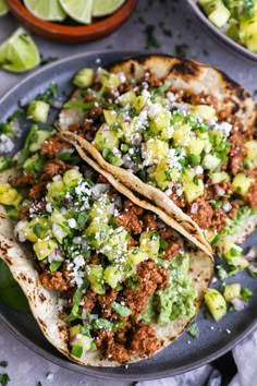 two tacos with meat, avocado and cilantro on a plate