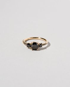 a gold ring with black stones on the side and two diamonds at the top, set in