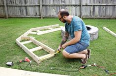 a man is working on some kind of wooden structure in the yard with his tools