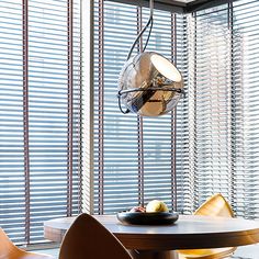 a dining room table and chairs in front of large windows with blinds on the outside