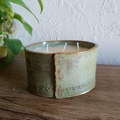 a candle is sitting on a table next to a potted plant