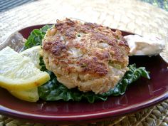 crab cakes with lemon wedges and greens on a red plate, ready to be eaten