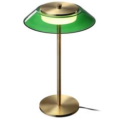 a green and gold lamp with a white light on the top, sitting on a metal base