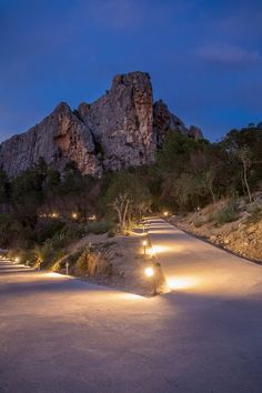 several lights are lit up on the side of a road near some mountains at night