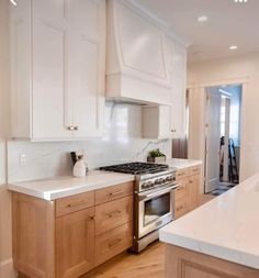 a kitchen with white counter tops and wooden cabinetry, along with a stainless steel stove top oven