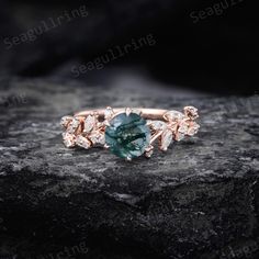 a green and white diamond ring sitting on top of a rock