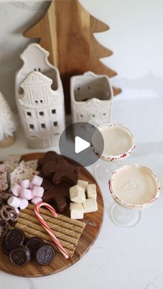 a wooden plate topped with chocolates and marshmallows on top of a table