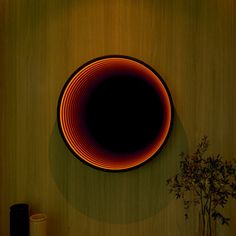 a black and orange plate sitting on top of a wooden table next to a vase