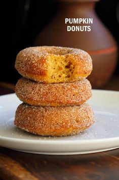 three sugary donuts stacked on top of each other with the words pumpkin donuts above them