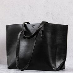 This spacious and super soft vegan leather tote coordinates with any ensemble. Features a tie closure, interior zipper pocket + phone pouch. This makes a great laptop bag, diaper bag, or weekender when you're on the go. 100% Vegan Leather 13" drop shoulder strap 12.5" h x 20" w x 6.5" d Features a tie closure, interior zipper pocket + phone pouch Trendy On-the-go Tote Laptop Bag, Business Weekender Bag Rectangular, Shopping Diaper Bag With Adjustable Strap Tote, Rectangular Faux Leather Laptop Bag For Travel, Large Capacity Tote Diaper Bag For Shopping, Soft Leather Tote Laptop Bag For Travel, Faux Leather Laptop Bag For Everyday Use, Business Weekender Tote Bag, Everyday Use Faux Leather Laptop Bag