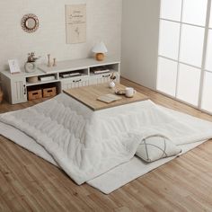 a living room with white walls and wood flooring on the wooden floor, there is a coffee table in the middle