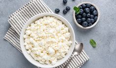 blueberries and cottage cheese in a bowl on a towel next to a cup of milk