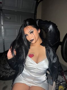 a woman in a white dress and black leather jacket posing for the camera with her hands behind her head