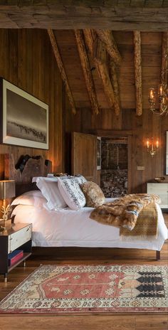 a bedroom with wood paneling and white bedding, chandelier hanging from the ceiling