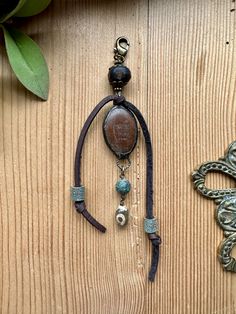 a wooden table topped with an ornate necklace and keychain hanging from it's side