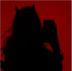 the silhouette of a woman holding a cell phone up to her face with long hair