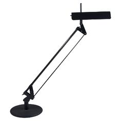 a black desk lamp on a white background with clippings to the side and one arm extended