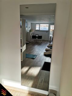 an open door leading to a living room with hardwood floors and furniture in the background