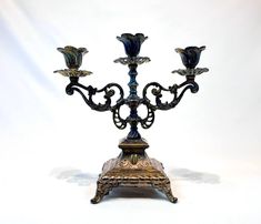 an ornate metal candelabra with four candles on it's stand, against a white background