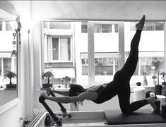 a woman is doing pivots on a treadmill in a room with large windows