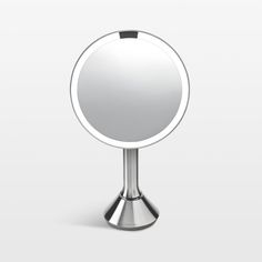 a round mirror sitting on top of a metal stand