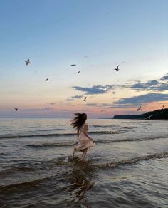 a woman is running through the water at sunset