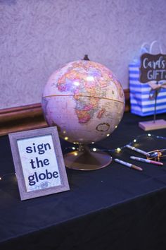 a table topped with a globe and some writing on it's side next to other items