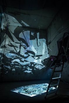 a ladder stands in front of a projected image on the wall, with light coming through it