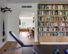 a home gym with bookshelves and exercise equipment on the floor in front of it