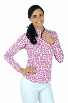 a woman in white pants and a pink shirt is posing with her hands on her hips